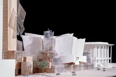 An eye-level view of a model of Walt Disney Concert Hall constructed in wood, acrylic, and paper suggests the dynamic form of the building juxtaposed against its urban context. Scale cars and trees afford realism.