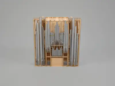 A scale model of an organ constructed in wood with pipes oriented vertically and painted to suggest the appearance of metal.