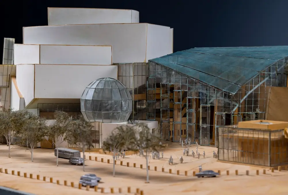 A detailed model of Walt Disney Concert Hall shows an early design for the building and its immediate environment, including scale figurines, cars, and landscaping.
