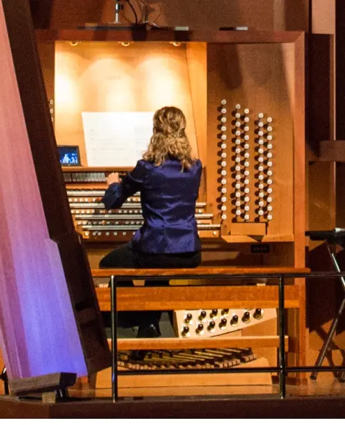 A smiling woman plays the organ in the Walt Disney Concert Hall.