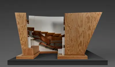 A scale model in wood represents an interior section of Walt Disney Concert Hall. Small metal figurines populate the model, representing concertgoers and orchestral players