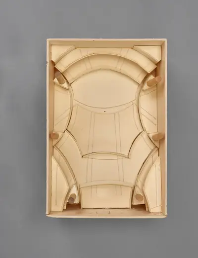 A model of the Walt Disney Concert Hall interior constructed in simple materials schematically illustrates the rectangular dimensions of the room and the arrangement of seats, balconies, and the stage within it. Printed lines suggest the placement of aisles, stairs, and other details.