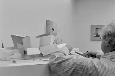 With scissors in hand, Frank Gehry makes a cut in a piece of the model of Walt Disney Concert Hall constructed in paper