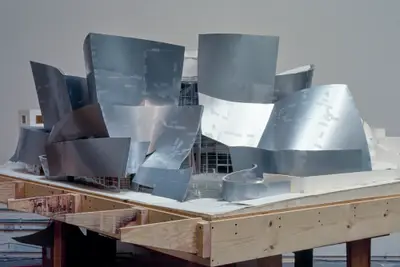 A eye-level view of a model of Walt Disney Concert Hall constructed in metal-foil paper, acrylic, and wood nearly suggests a completed building. Tape marks, however, suggest that this is still a work-in-progress.