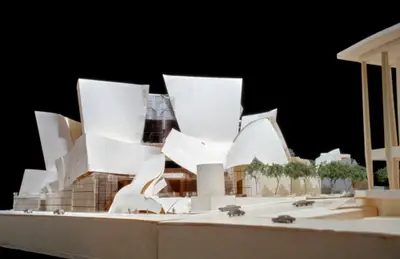 A pedestrian's-eye view of a model of Walt Disney Concert Hall roughly constructed in paper, acrylic, and wood suggests the dynamic appearance of the building. Scale cars, trees, and figurines afford realism.
