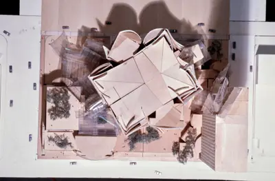 An aerial view of a model of Walt Disney Concert Hall constructed in wood, acrylic, and paper suggests the complex form of the building within its urban context. Scale cars and trees afford realism.