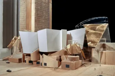 An eye-level view of a model of Walt Disney Concert Hall constructed in wood, acrylic, paper, and gold-colored metal suggests the dynamic form of the building. Scale cars and figurines afford realism.