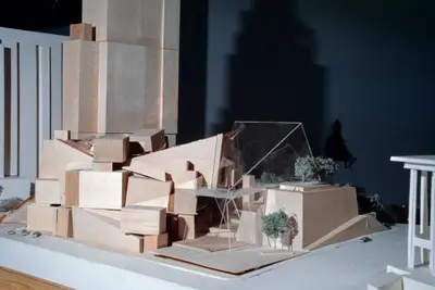 An eye-level view of a model of Walt Disney Concert Hall constructed in wood and acrylic suggests the appearance of a building composed of stacked wooden blocks. Scale cars and trees afford realism.