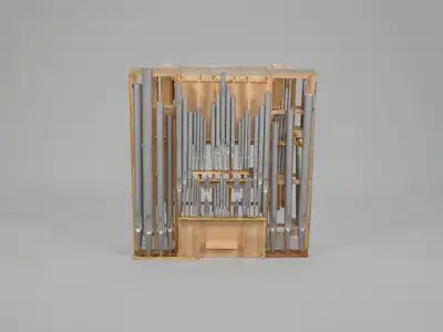 A scale model of an organ constructed in wood with pipes oriented vertically and painted to suggest the appearance of metal.