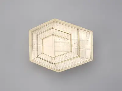 A model of the Walt Disney Concert Hall interior constructed in simple, beige materials schematically illustrates the roughly hexagonal shape of the room and the arrangement of seats, balconies, and the stage within it. Printed lines suggest the placement of aisles, stairs, and other details.